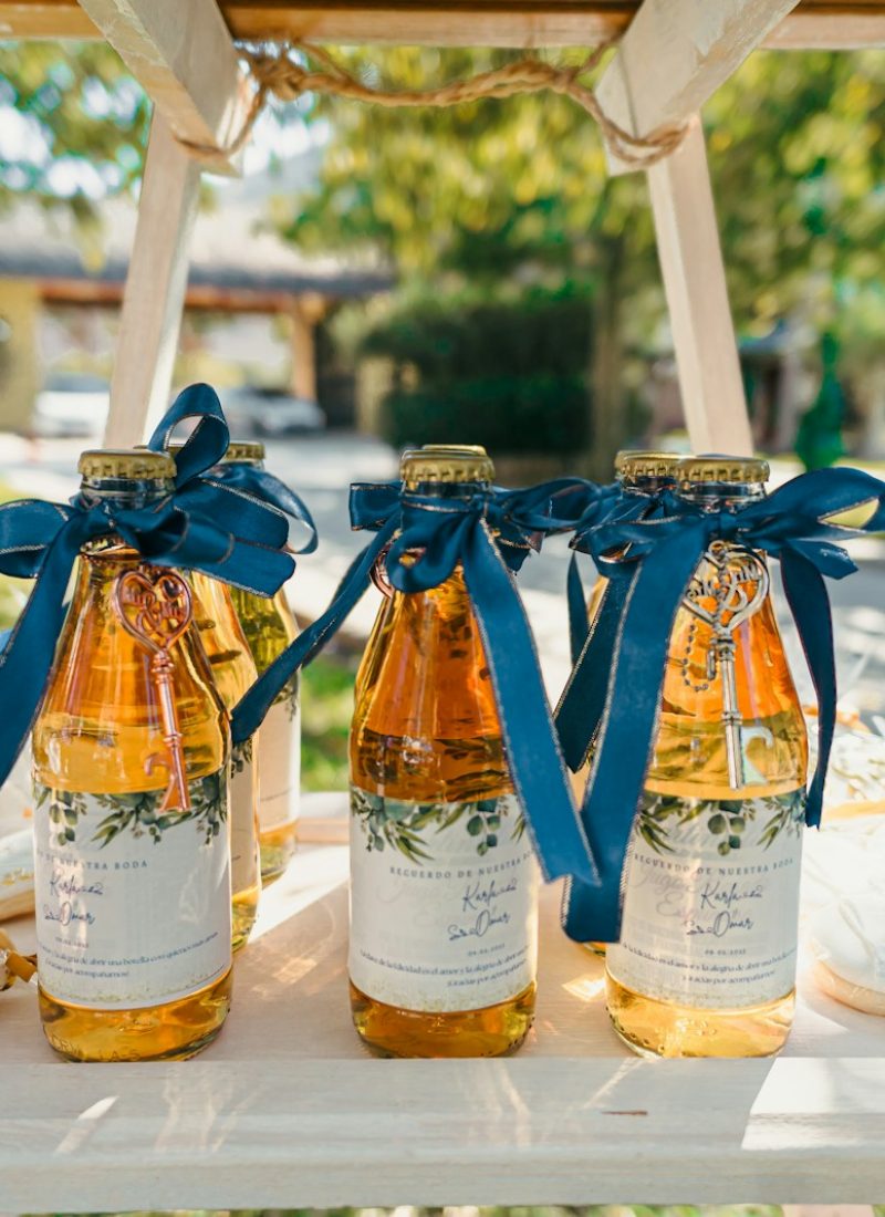 Three glass bottles with golden liquid and blue ribbons